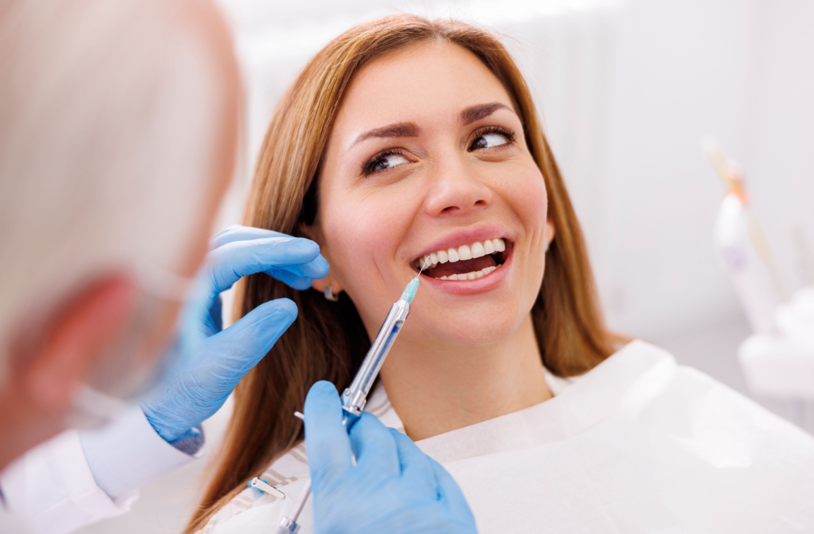 A patient smiles before receiving a dental numbing treatment.