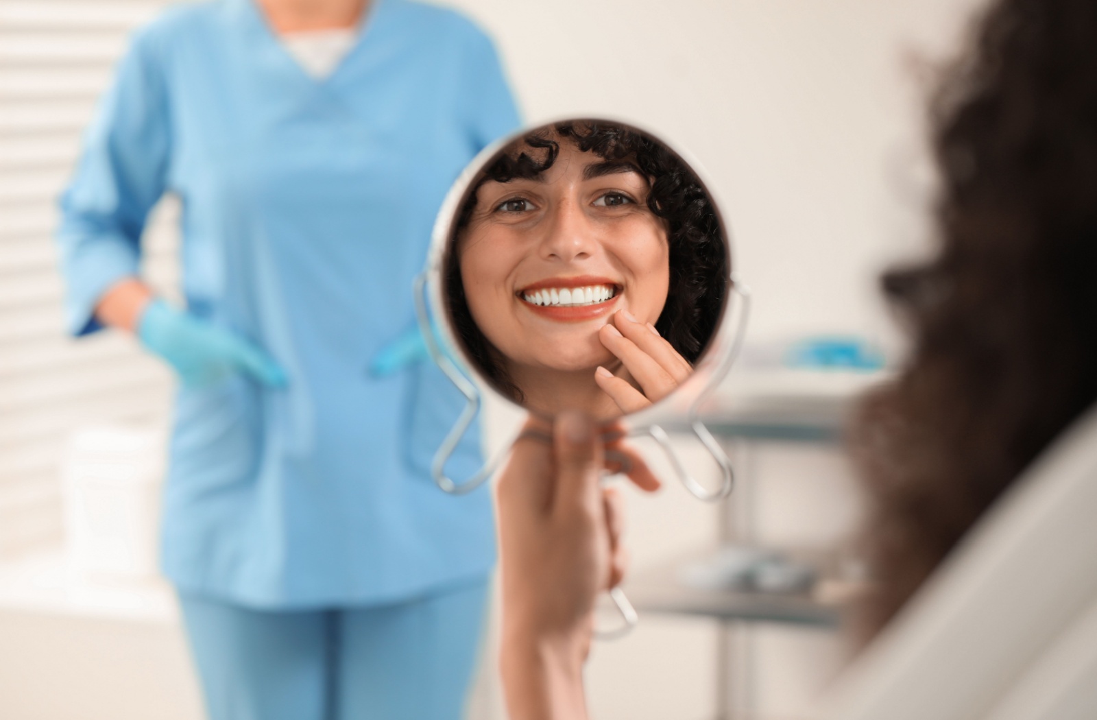 A dentist's hand holding up tooth shade matches to a patient's smile to ensure their dental crown matches their smile.